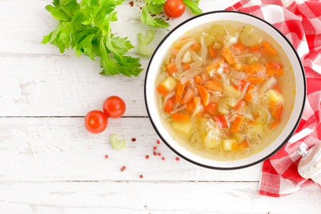 Vegetable soup. Healthy food, vegetarian dish. Vegetable soup with cabbage, potato, tomato, carrot, celery, pepper and green peas. Vegan diet menu. Top viewの写真素材