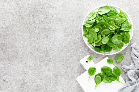 Fresh spinach leaves on white plate. Healthy vegan food. Top viewの写真素材
