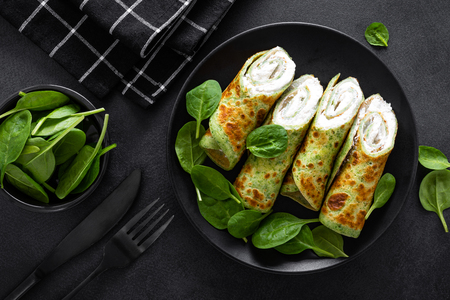 Savory crepes with spinach and feta cheese on black background, top viewの写真素材