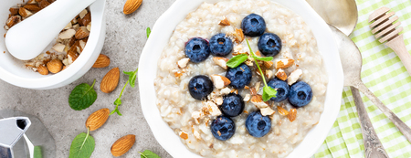 Oatmeal with fresh blueberry, almond nuts and honey for breakfast. Bannerの写真素材