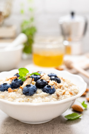 Oatmeal with fresh blueberry, almond nuts and honey for breakfastの写真素材