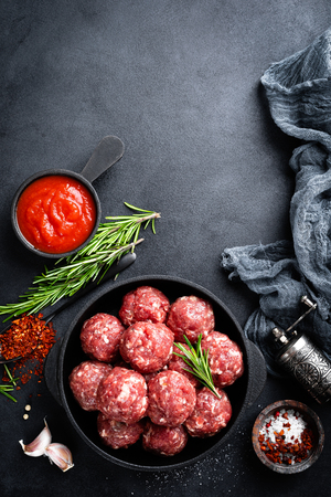 Fresh raw beef meatballs with spices and tomato sauceの写真素材