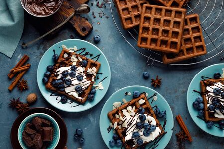 Chocolate belgian waffles with ice cream and fresh blueberry on blue background, top viewの写真素材