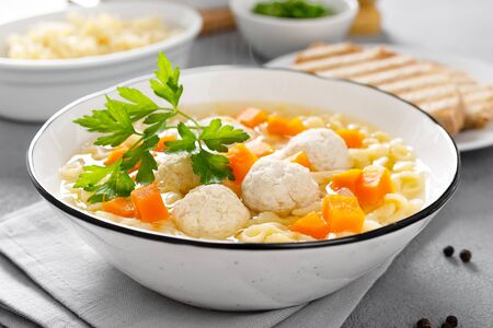 Hot chicken soup, broth with meatballs, carrot, pasta and fresh parsleyの写真素材