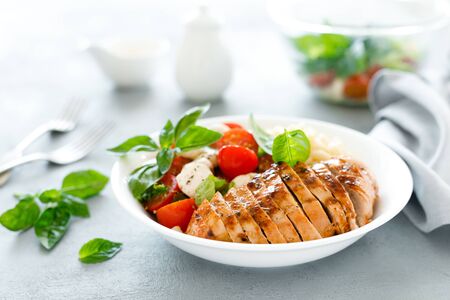 Grilled chicken lunch bowl with orange juice dressing, pasta and caprese saladの写真素材