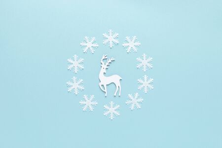Christmas, New Year or Noel holiday festive winter greeting card, deer and snowflakes on blue background, flat lay composition, top viewの写真素材