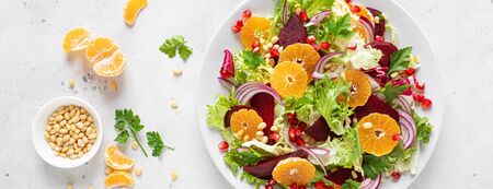 Christmas salad with boiled beet, red onion, tangerines, pomegranate, parsley, pine nuts and lettuce leaves, bannerの写真素材