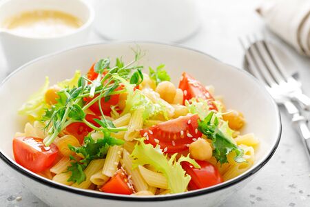 Pasta salad with fresh tomato, chickpea, lettuce and pea sprouts in lunch bowlの写真素材
