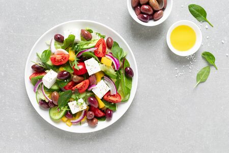 Greek salad with greens, olives and feta chesse on a white plate, top viewの写真素材