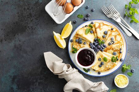 Crepes, thin pancakes with blueberry jam and fresh berries with lemon zestの写真素材