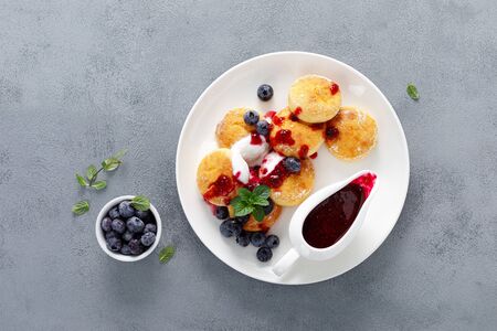 Baked cottage cheese pancakes, syrniki with yogurt, blueberry sauce and fresh berriesの写真素材