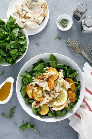 Chicken salad with spinach and crispy potatoes dressed with olive oil, garlic, lemon, onion and thymeの写真素材