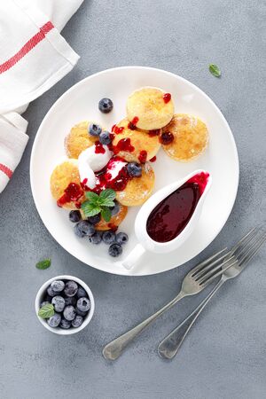 Baked cottage cheese pancakes, syrniki with yogurt, blueberry sauce and fresh berriesの写真素材