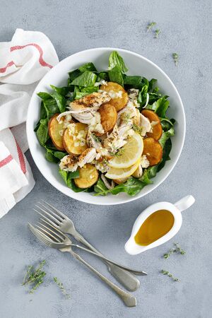 Chicken salad with spinach and crispy potatoes dressed with olive oil, garlic, lemon, onion and thymeの写真素材
