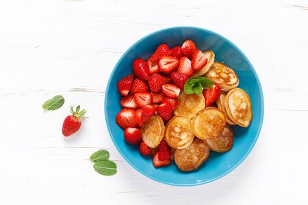 Pancake cereal, mini pancakes with fresh strawberry in a bowl with maple syrupの写真素材
