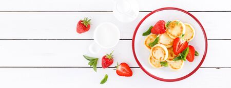 Cheese pancakes, fritters or syrniki with fresh strawberry and yogurt. Healthy and tasty breakfast. Bannerの写真素材