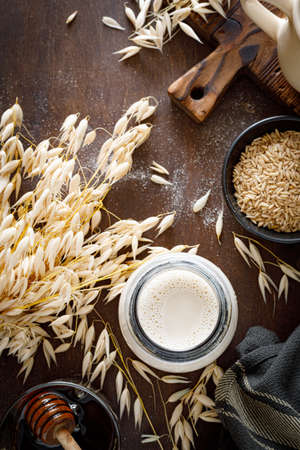 Vegan oat milk in glass bottle and ingredients for cooking. Healthy vegetarian non-dairy drink or beverage. Alternative milkの写真素材