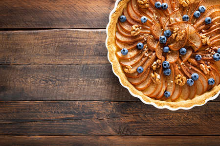 Thanksgiving pear tart, pie or cake with fresh pears and blueberry, cinnamon and walnutsの写真素材
