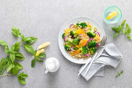 Vegan quinoa and broccoli warm salad with oranges and fresh onion, top down view