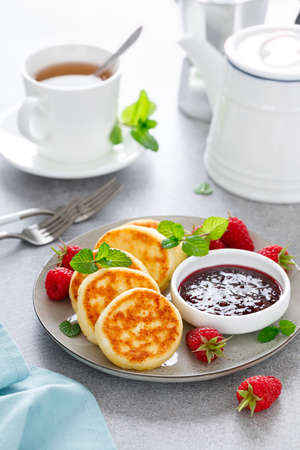 Cottage cheese pancakes, sweet curd fritters with berries, syrniki with jam and fresh raspberry on breakfast tableの写真素材