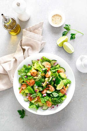 Shrimps salad with green lettuce, cucumbers and avocado, dressed with lime juice, healthy and tasty food, top viewの写真素材