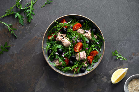 Fresh vegetable salad with tuna, arugula, olives and tomatoes. Healthy food concept, top down viewの写真素材