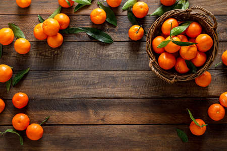 Tangerines, fresh mandarin oranges, clementines with leaves on wooden background. Top view, copy spaceの写真素材