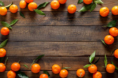 Tangerines, fresh mandarin oranges, clementines with leaves on wooden background. Top view, copy spaceの写真素材