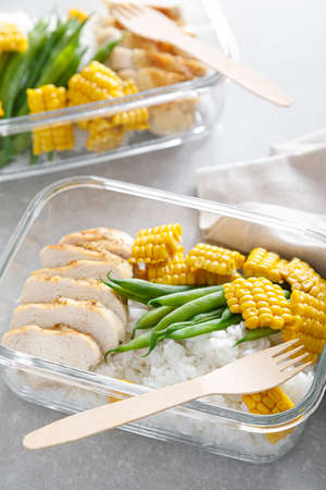 Lunch box containers with grilled chicken, rice and green beans with cornの写真素材