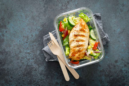 Lunch box containers with grilled chicken breast and fresh vegetable saladの写真素材
