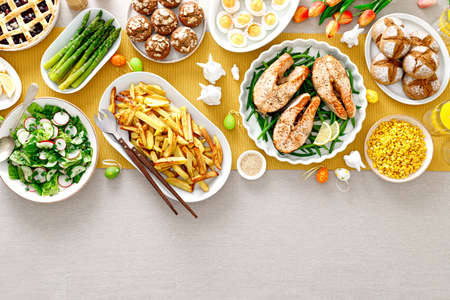 Easter festive table with salmon, asparagus, salad, potato, muffins and berry pieの写真素材