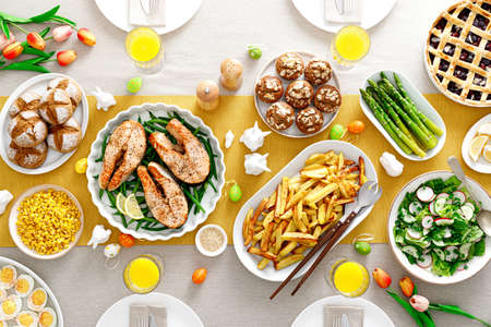 Easter festive table with salmon, asparagus, salad, potato, muffins and berry pieの写真素材