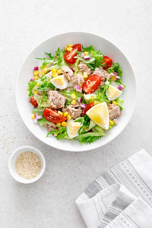 Tuna salad with boiled egg, tomato, lettuce, corn and red onion. Healthy and detox food concept. Ketogenic diet. Fresh vegetable salad bowl on white background. Top viewの写真素材