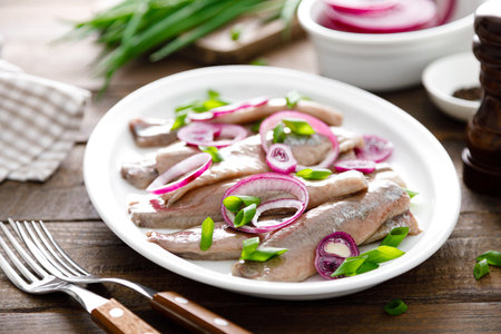 Salted, marinated herring fillet with onion on plateの写真素材