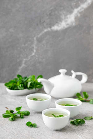 Herbal mint tea in small traditional chinese cups and fresh leaves, healthy antioxidant drinkの写真素材