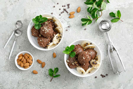 Chocolate and banana fruit ice cream with almond nuts served in bowls, top view