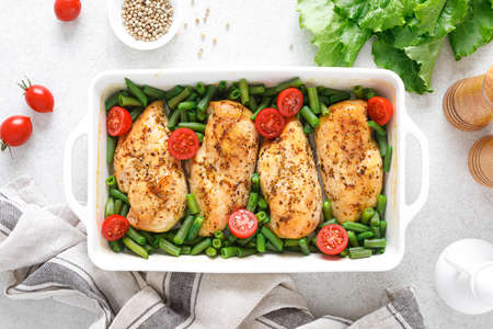 Chicken meat, breast baked and green beans with tomatoes on white background. Keto diet. Healthy food. Top view.の写真素材