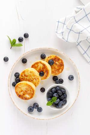 Cottage cheese or curd fritters with honey and fresh blueberry. Healthy diet food, breakfast. Top view.の写真素材