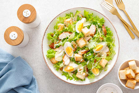 Caesar salad with grilled chicken breast, hard-boiled egg, croutons, parmesan cheese, green salad lettuce and dressingの写真素材
