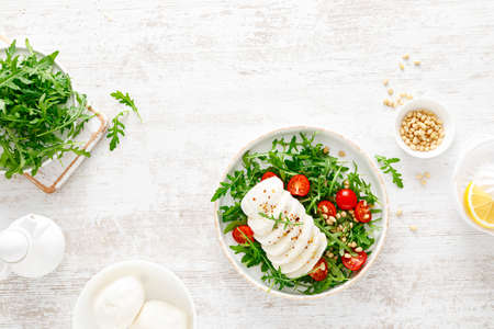 Salad with arugula, mozzarella cheese and pine nuts. Breakfast. Ketogenic, keto or paleo diet. Healthy food. Top viewの写真素材