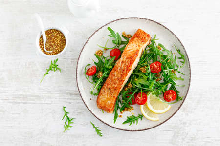 Salmon fish fillet grilled and fresh vegetable tomato salad with arugula. Healthy food. Ketogenic diet. Lunch. Top viewの写真素材