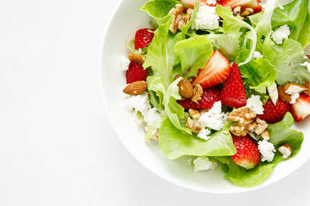 Strawberry and cottage cheese fresh fruit salad with walnut, almond and lettuce, top down view, flat...