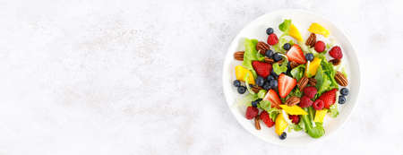 Fruit and berry salad with strawberry, blueberry, raspberry, mango and pecan nuts. Healthy food, diet. Top view. Bannerの写真素材