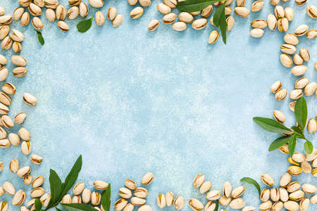 Pistachios. Pistachio nuts with green leaves. Healthy natural vegetarian organic food. Top view, copy spaceの写真素材