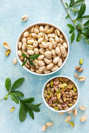 Pistachios. Whole pistachios with green leaves and pistachio nut kernels. Healthy natural vegetarian organic food. Top view, copy spaceの写真素材