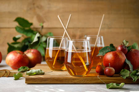 Apple juice in a glass and fresh fruits with leaves