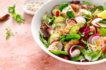 Salmon salad bowl with fresh radish, cucumber, red onion and green mixed leafy vegetables. Healthy diet food, lunch menuの写真素材