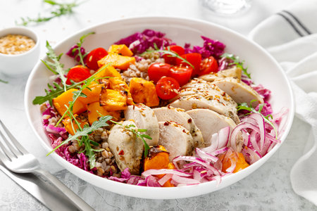 Chicken breast fillet and buckwheat bowl, grilled butternut squash and fresh vegetable salad with arugula and tomatoes, healthy food, lunch menu, top viewの写真素材