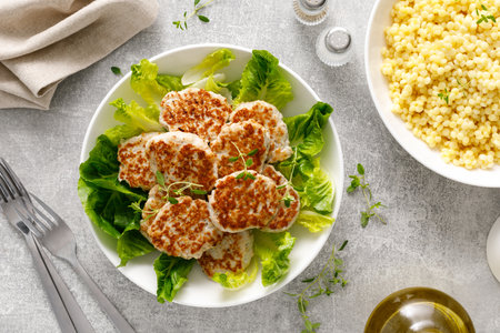 Chicken patties, cutlets with fresh romaine lettuce salad and couscous, top down viewの写真素材