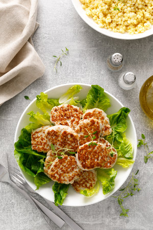 Chicken patties, cutlets with fresh romaine lettuce salad and couscous, top down viewの写真素材